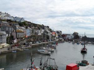 a group of boats docked in a river with houses at Harbour Tavern Penthouse in Mevagissey