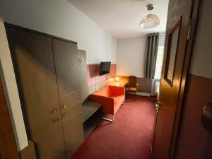 ein Hotelzimmer mit einem orangenen Stuhl und einem Schrank in der Unterkunft Hotel Podkowa in Breslau