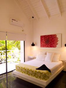 um quarto com uma cama com um quadro de flores vermelhas na parede em Casa de las Flores tropical em San Andrés