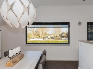 een eetkamer met een tafel en een raam bij Beautiful luxury holiday home with rural character in Ruinerwold