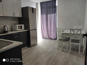 uma cozinha com uma mesa e cadeiras e um frigorífico em Apartmets Domovik Вместительная трьохкомнатная квартира em Mukacheve