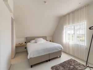 um quarto branco com uma cama e uma janela em Spacious holiday home in Aardenburg with terrace em Aardenburg