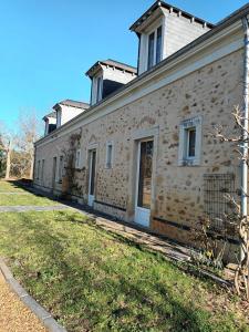 - un vieux bâtiment en pierre avec une pelouse dans l'établissement Bellopratainnes, à Bazouges-sur-le-Loir