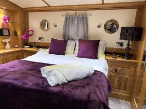 ein Schlafzimmer mit einem großen Bett mit violetter Bettwäsche in der Unterkunft Luxury boat - The Thistle Dream in Uxbridge