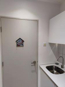 a kitchen with a sink and a door with a sign on it at Swiss Home Horizon Suite 1 in Sepang