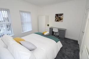 een witte slaapkamer met een wit bed en een bureau bij Belfast Cozy Home in Belfast