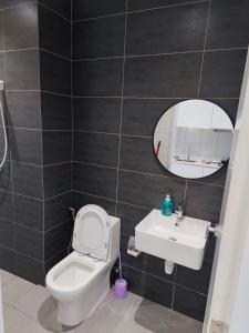 a bathroom with a toilet and a sink and a mirror at Swiss Home Horizon Suite 1 in Sepang