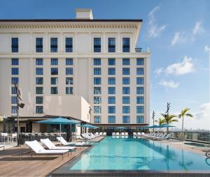 a hotel with a swimming pool and lounge chairs at Loews Coral Gables Hotel in Miami