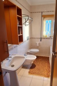 ein Bad mit einem Waschbecken, einem WC und einem Fenster in der Unterkunft Vivenda do relaxo in Freiria