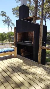 una chimenea en la parte superior de una terraza con un banco en Juanillos cabaña con hogar a leña, en Punta del Diablo