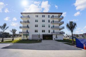 un gran edificio blanco con balcones y palmeras en The Harbor Condo 305 - Premier, en St Pete Beach