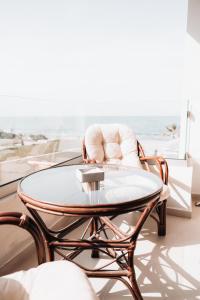 een salontafel en stoelen in een woonkamer met uitzicht op de oceaan bij Indigo Seaside Experience in Adelianos Kampos