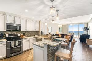 a kitchen with white cabinets and a kitchen island with a view of the ocean at Spanish Key 204 in Perdido Key