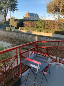 a red railing with a blue table on a balcony at Top appartement 2 pièces in La Richardais