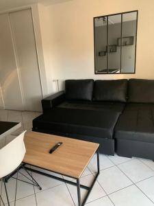 een woonkamer met een zwarte bank en een salontafel bij Top appartement 2 pièces in La Richardais