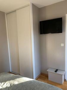 een slaapkamer met een bed en een flatscreen-tv aan de muur bij Top appartement 2 pièces in La Richardais
