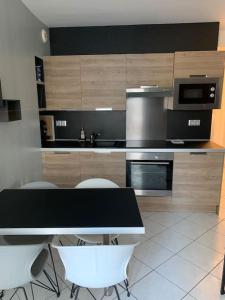 eine Küche mit einem schwarzen Tisch und weißen Stühlen in der Unterkunft Top appartement 2 pièces in La Richardais