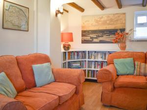 a living room with a couch and a book shelf at Pump Cottage in Brancaster