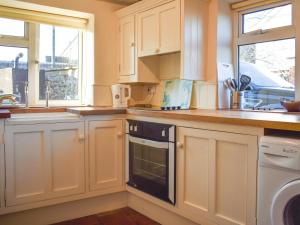 a kitchen with white cabinets and a dishwasher at Pump Cottage in Brancaster