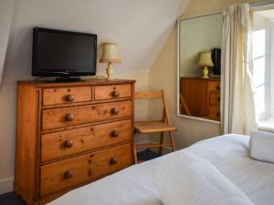a bedroom with a dresser with a television on it at Pump Cottage in Brancaster