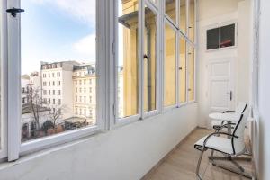 Cette chambre blanche dispose d'une chaise et d'une fenêtre. dans l'établissement Prague Centre Apartments, à Prague