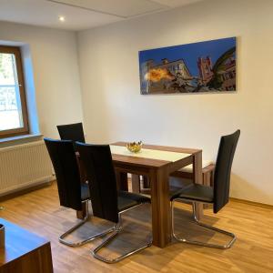 uma sala de jantar com uma mesa de madeira e cadeiras pretas em Körners Ferienwohnung am Fuße des Voithenbergs em Furth im Wald