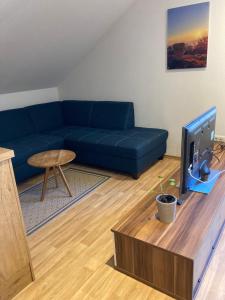 a living room with a blue couch and a tv at Körners Ferienwohnung am Fuße des Voithenbergs in Furth im Wald