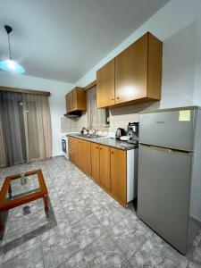 cocina con armarios de madera y nevera blanca en Elli's apartments, en Antimácheia