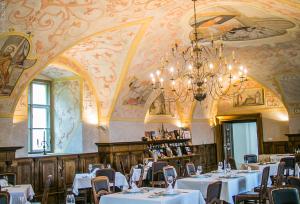 una sala da pranzo con tavoli, sedie e lampadario a braccio di Sopron Monastery Hotel a Sopron