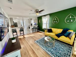 a living room with a yellow couch and a green wall at Plush Downtown ATL 2BD Home w/ FREE PKNG in Atlanta