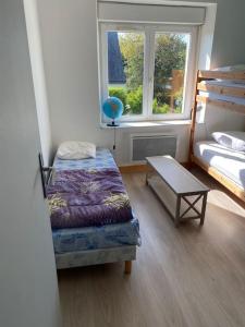a bedroom with a bed and a table and a window at Maison avec jardin in Crozon