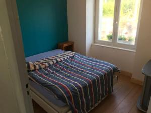 a bedroom with a bed with a blue wall and a window at Maison avec jardin in Crozon