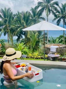 a woman sitting at a table in the water near a pool at Bintana sa Paraiso Binunsaran in Mambajao