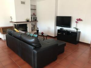 a living room with a black leather couch and a tv at Casa do Olival in Peso da Régua