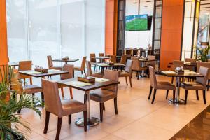 a restaurant with tables and chairs and a television at Holiday Inn Guayaquil Airport, an IHG Hotel in Guayaquil