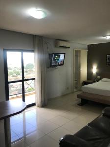 1 dormitorio con 1 cama y TV en la pared en Crystal Place, en Goiânia