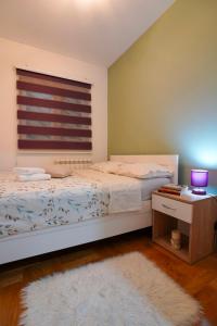 a bedroom with a bed and a table and a window at Apartman Nemanja in Bijeljina