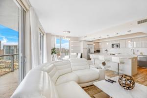 Una sala de estar con un sofá blanco y una cocina. en Beachwalk Resort - BRIGHT OCEAN VIEW CONDO LUXURY 3BDR, en Hallandale Beach