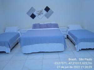 2 camas en una habitación de color azul en Acomodações Anfitriã, en Indaiatuba