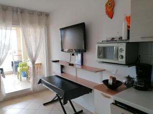 cocina con escritorio y TV en la pared en Appartement Résidence Les Eucalyptus, en LʼÎle-Rousse