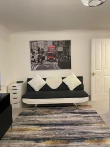 a living room with a black couch and a red bus at Stunning Studio Flat - Free Parking - 3 min from Sutton Station in Sutton