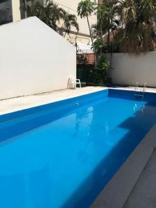 a blue swimming pool with a white wall and trees at Moreno House in Corrientes