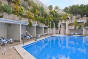 a large swimming pool with chairs and a building at Apartamento Alicante Beach in Alicante