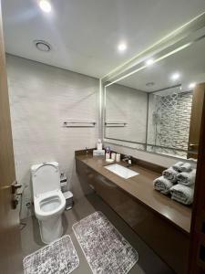 y baño con aseo y espejo grande. en Luxury Apartment with Part Lake View, en Sharjah