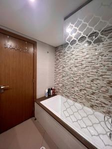 baño con bañera y pared de piedra en Luxury Apartment with Part Lake View, en Sharjah