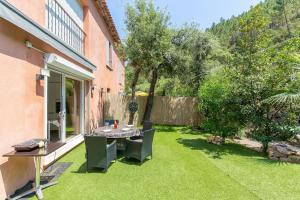 un jardin avec une table et des chaises sur la pelouse dans l'établissement 2 pièces climatisé à 200m des plages, à Théoule-sur-Mer