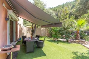 a patio with a table and chairs on a lawn at 2 pièces climatisé à 200m des plages in Théoule-sur-Mer