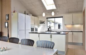 cocina con armarios blancos, mesa y sillas en Stunning Home In Ringkbing With Sauna, en Klegod