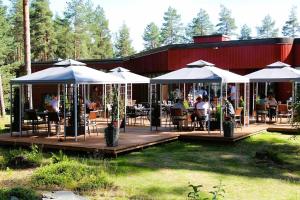 a restaurant with tables and umbrellas on a deck at Herttua Hotel and Spa in Kerimäki
