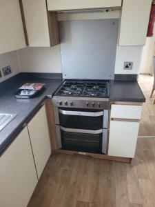 a kitchen with a stove and white cabinets at Point Clear 4 bed Static Caravan in Saint Osyth +21 photos